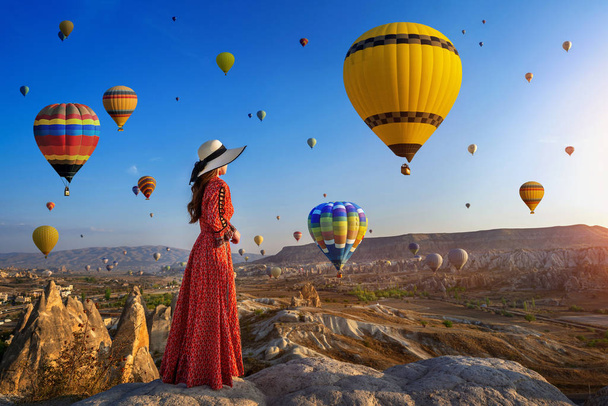Beautiful girl standing and looking to hot air balloons in Cappadocia, Turkey. - Fotó, kép