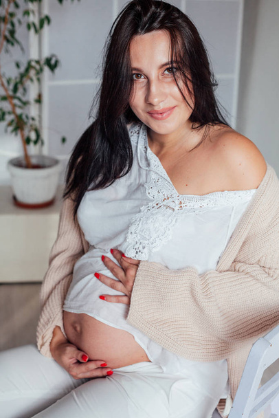 mooie zwangere vrouw in een witte kamer - Foto, afbeelding