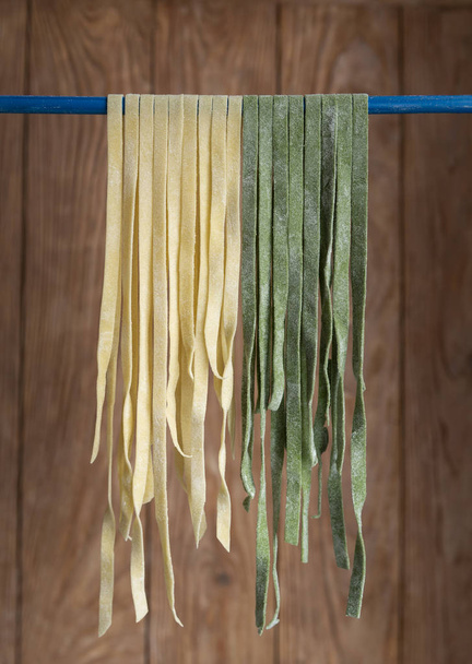 View of homemade pasta; hanging traditional and colored with spinach pasta  - Photo, Image
