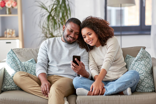 happy couple with smartphone and earphones at home - Foto, Bild