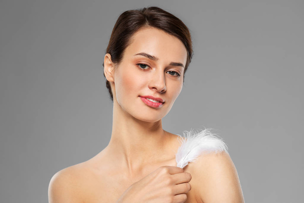 beautiful woman with feather touching her shoulder - Fotografie, Obrázek