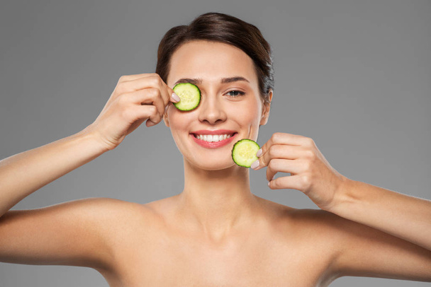 beautiful woman making eye mask of cucumbers - Фото, зображення
