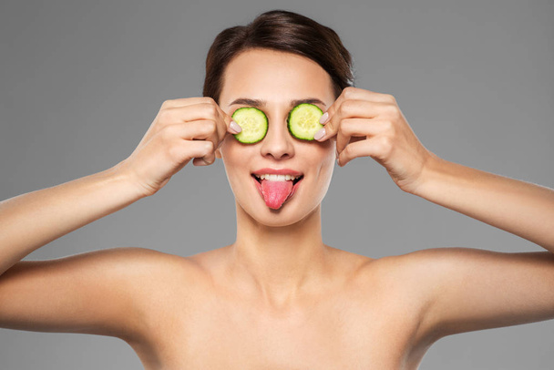 beautiful woman making eye mask of cucumbers - Foto, afbeelding