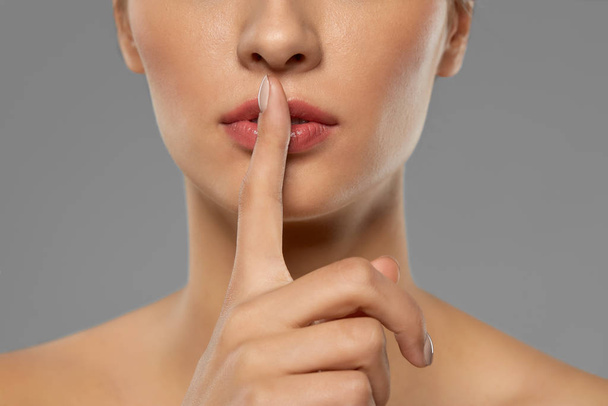 beautiful young woman holding finger on lips - Foto, imagen