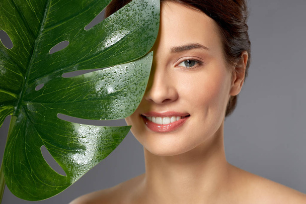beautiful young woman with green monstera leaf - Valokuva, kuva