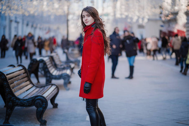 Retrato de una joven morena con un abrigo rojo en una plaza roja en el centro de Moscú
 - Foto, Imagen