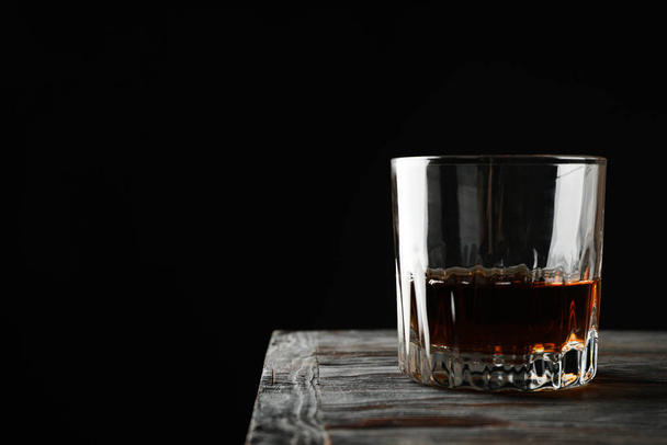 Glass of whiskey on wooden background, space for text - Foto, Imagen