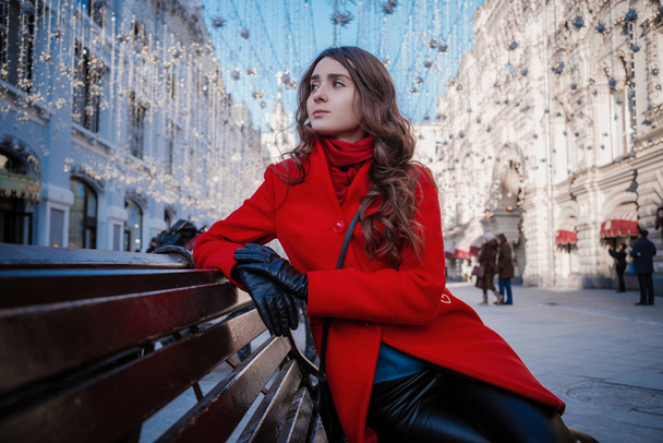 Πορτρέτο μιας νεαρής μελαχρινής γυναίκας με κόκκινο παλτό σε μια κόκκινη πλατεία στο κέντρο της Μόσχας - Φωτογραφία, εικόνα