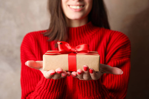 Woman with smile holding gift boxes on brown background, closeup - Foto, Bild