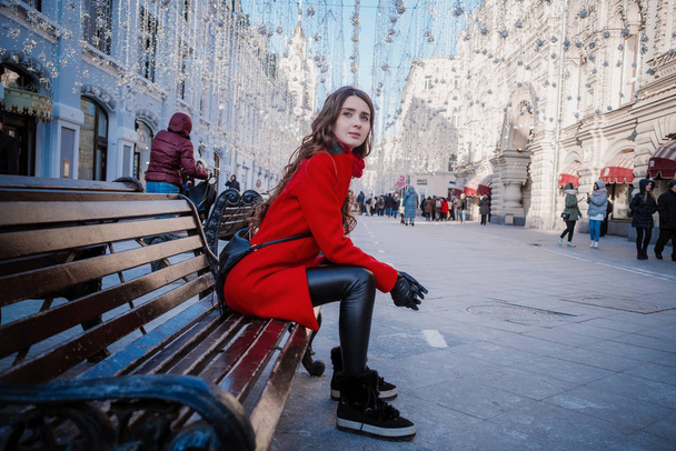 モスクワの中心にある赤い正方形の上に赤いコートの若いブルネットの女性の肖像画 - 写真・画像