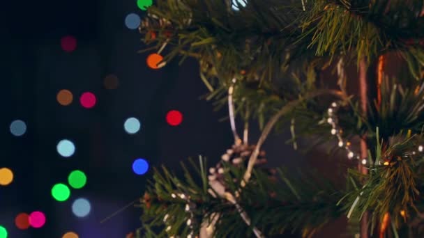 Een meisje is opknoping versieren kerstversiering op kerstboom, close-up schot, met vonkende Led lamp verlichting plek in de donkere zwarte achtergrond. - Video