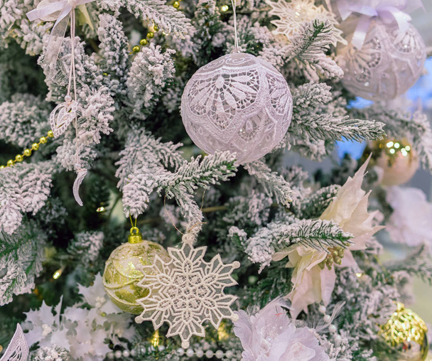 Árbol de Navidad con ramas nevadas, decorado con bolas de encaje blanco, juguetes y copos de nieve
 - Foto, Imagen