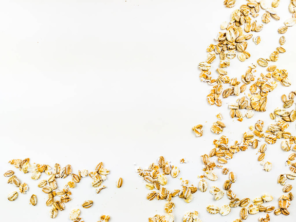 Healthy and golden yellow oat grain flake cereal placed on one corner of the image on a white background forming a frame of healthy food - Fotoğraf, Görsel