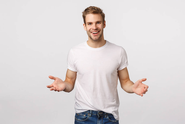 Man extending hands forward to hold something, leaning to product, helping out friend carry heavy boxes, smiling joyfully, friendly looking forward, standing white background - Photo, image