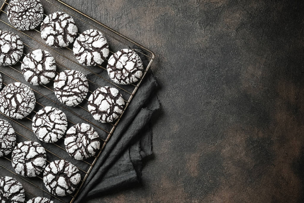 Pudra şekerli çikolatalı buruşuk kurabiyeler. Çatlamış çikolatalı bisküviler arka plandaki demir kafes üzerinde fotokopi alanı - Fotoğraf, Görsel