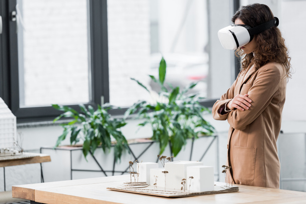 side view of virtual reality architect in virtual reality headset looking at model of house  - 写真・画像