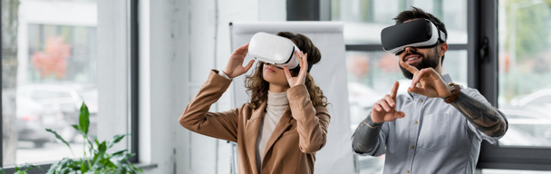 plano panorámico de los arquitectos de realidad virtual sonrientes en auriculares de realidad virtual apuntando con el dedo
  - Foto, imagen