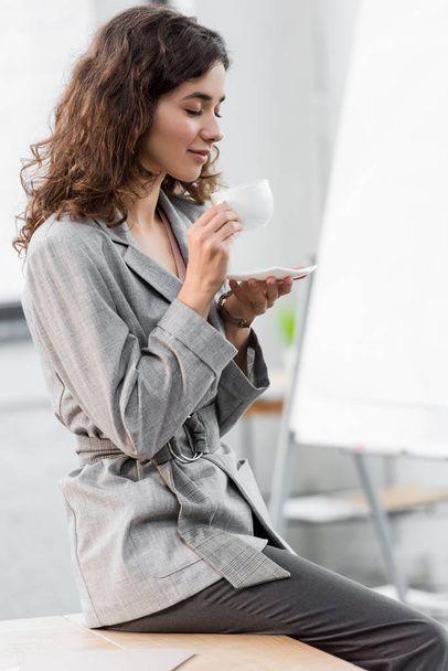 smiling and attractive account manager with closed eyes smelling coffee  - 写真・画像