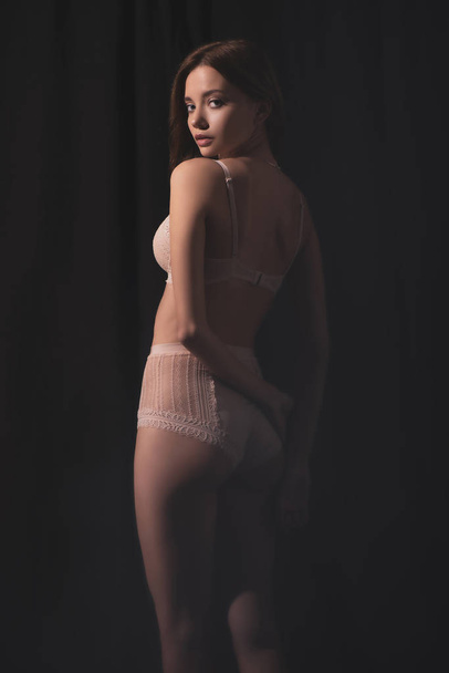 sexy young woman in lingerie looking at camera while posing on black background  - Foto, afbeelding
