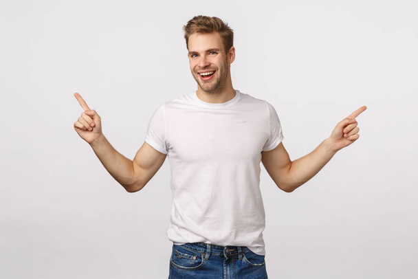 Handsome outgoing smiling blond caucasian male, laughing carefree and delighted, have large opportunities, two ways or choices, pointing sideways, give advice, show left and right product promo - Photo, Image