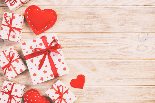 Valentin ou autre cadeau de vacances fait à la main en papier avec des cœurs rouges et une boîte cadeau dans un emballage de vacances. Coffret cadeau sur table en bois orange vue du dessus avec espace de copie, espace vide pour le design
 - Photo, image