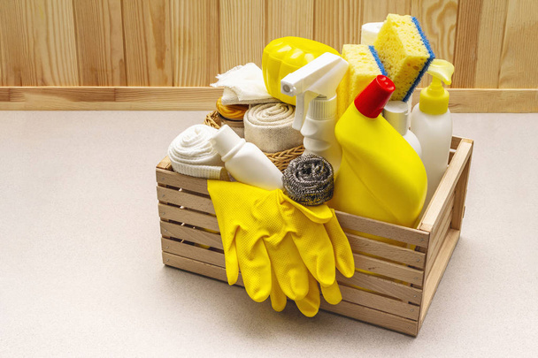 House cleaning product in wooden box. Spray, bottle, gloves, dishwashing sponge, scraper, gel air freshener. Stone concrete background - Photo, Image