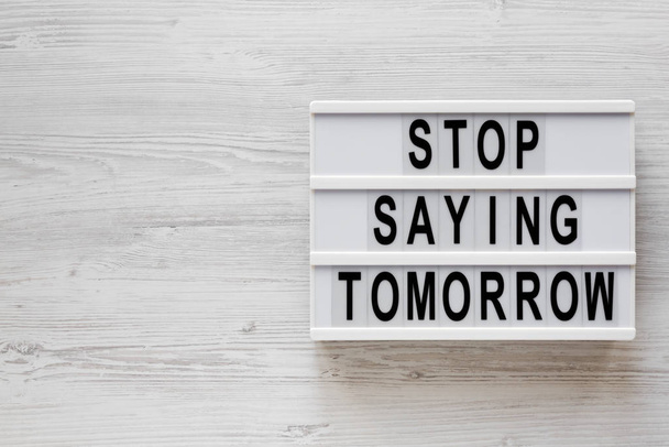 "Σταματήστε να λέτε αύριο" λέξεις σε ένα lightbox σε ένα λευκό ξύλινο sur - Φωτογραφία, εικόνα