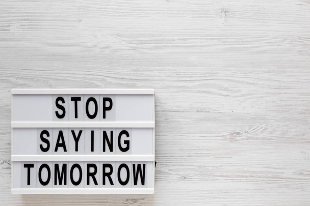 'Stop saying tomorrow' words on a lightbox on a white wooden sur - Photo, Image