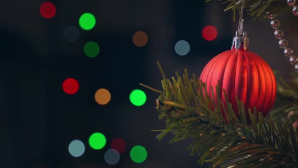 Mooie versierde kerstboom met opknoping bauble en sprankelende Led tekenreeks lamp verlichting plek in donker, zwarte achtergrond, macro, close-up, 4k. - Video