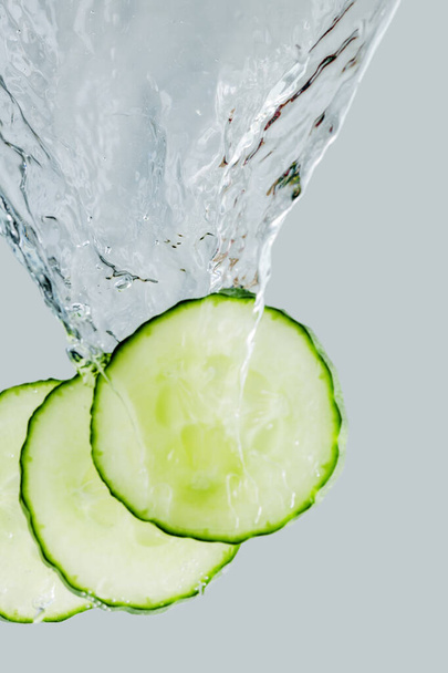 Three cucumber slices falling into the water cut - Fotografie, Obrázek
