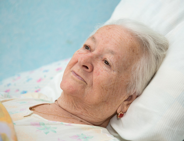 Стара хвора жінка лежить в ліжку
 - Фото, зображення