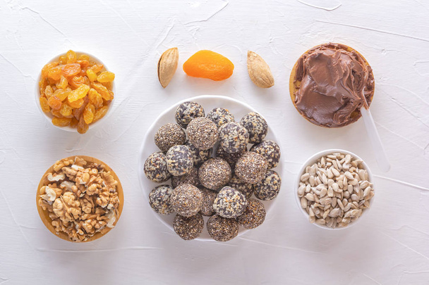 Mordeduras naturales saludables de energía cruda, pasta de chocolate y mezcla de frutas secas con nueces en una mesa blanca. Vista superior
 - Foto, imagen