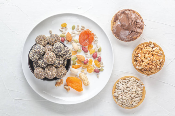 Morsi naturali sani di energia grezza, pasta di cioccolato e mix di frutta secca con noci su un tavolo bianco. Vista dall'alto
 - Foto, immagini