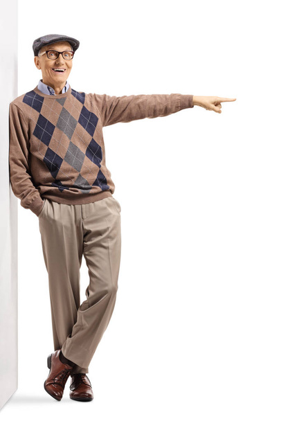 Senior man leaning on a wall and pointing to the side - 写真・画像