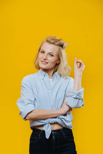Portrait of an attractive blonde woman with a curious look over yellow - Foto, afbeelding