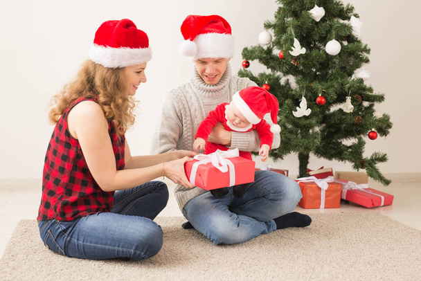 Счастливая пара с ребенком празднуют Рождество вместе дома
. - Фото, изображение