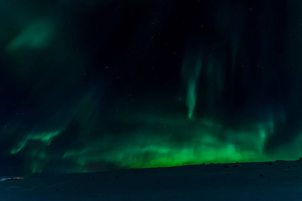 Aurora borealis in night northern sky. Ionization of air particles in the upper atmosphere. - Photo, Image