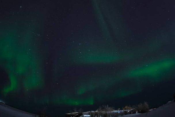 Aurora Borealis na nocnym niebie północnym. Jonizacja cząstek powietrza w górnej części atmosfery. - Zdjęcie, obraz