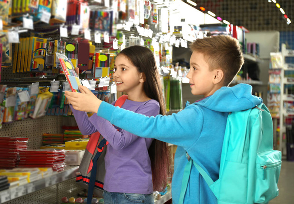 Little children choosing school stationery in supermarket - Fotó, kép