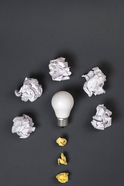new idea concept with crumpled office paper and white light bulb on grey background. Creative solution during brainstorming session concept. Flat lay, top view, copy space - Photo, Image