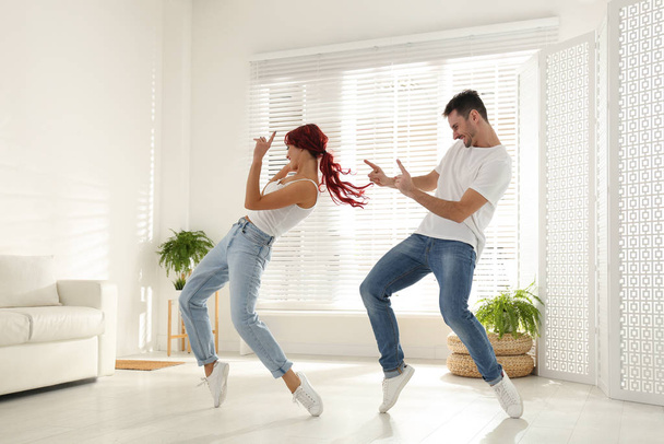 Beautiful young couple dancing in living room - Zdjęcie, obraz
