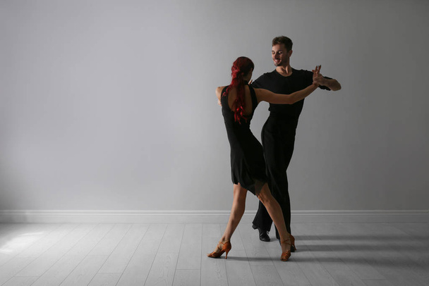 Beautiful young couple dancing near light wall. Space for text - Foto, imagen