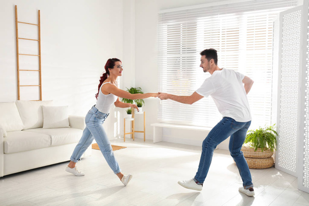 Beautiful young couple dancing in living room - Fotó, kép