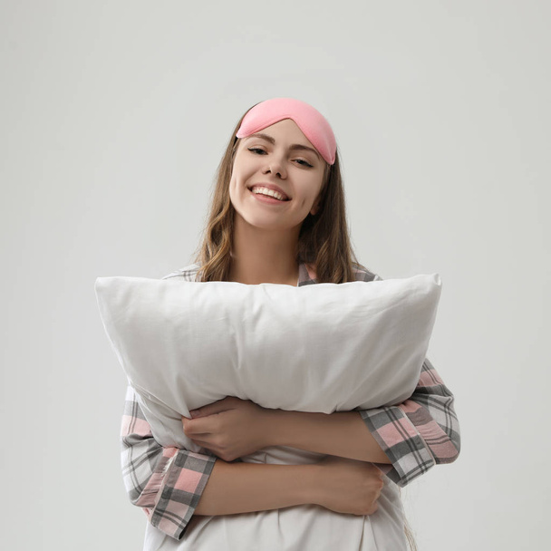 Beautiful woman with pillow on light grey background. Bedtime - Foto, Imagem