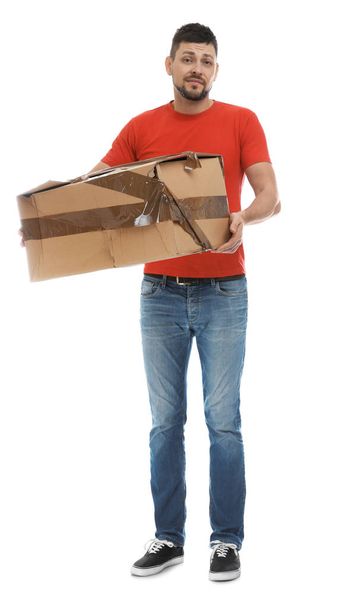 Emotional courier with damaged cardboard box on white background. Poor quality delivery service - Photo, Image