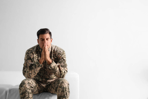 Stressed military officer sitting on sofa against white backgrou - Photo, image