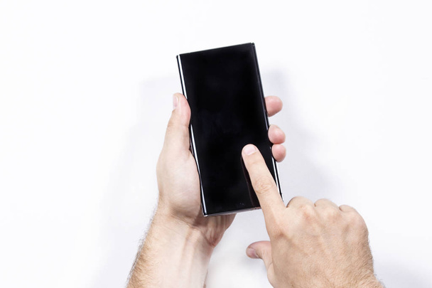 Man holding smartphone fehér háttér, közelkép a kéz. - Fotó, kép
