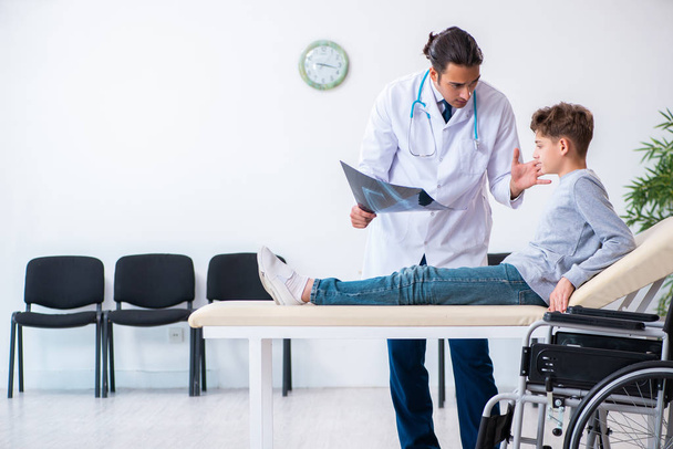 Młody lekarz pediatra i chłopiec na wózku inwalidzkim - Zdjęcie, obraz