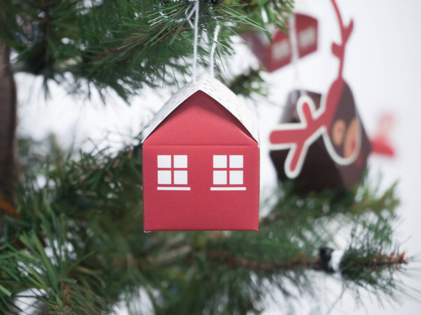 クリスマスツリーにかかってWindows付きの赤い紙の家。新しい住宅、住宅ローン、不動産購入、クリスマスと新年の概念 - 写真・画像