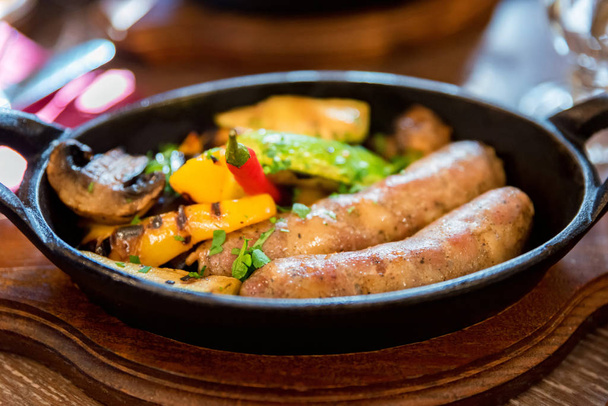 Grilled fried sausages kupaty on iron skillet grill with vegetables - Foto, Imagem